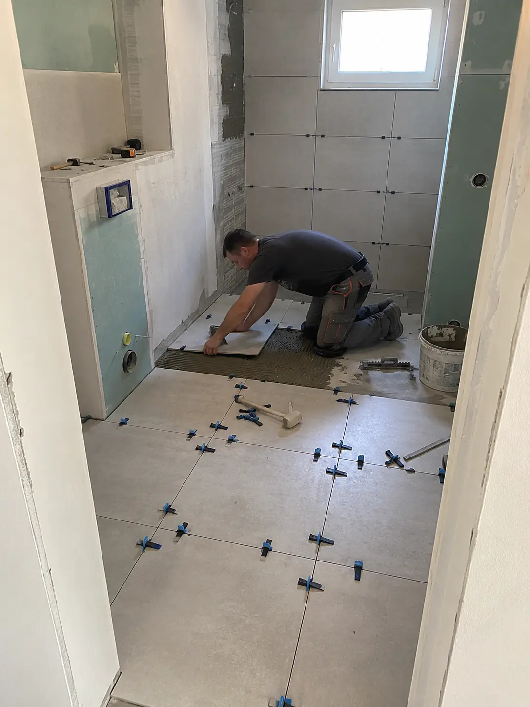 Fliesenleger beim Verlegen von Bodenfliesen im Badezimmer Hamburg