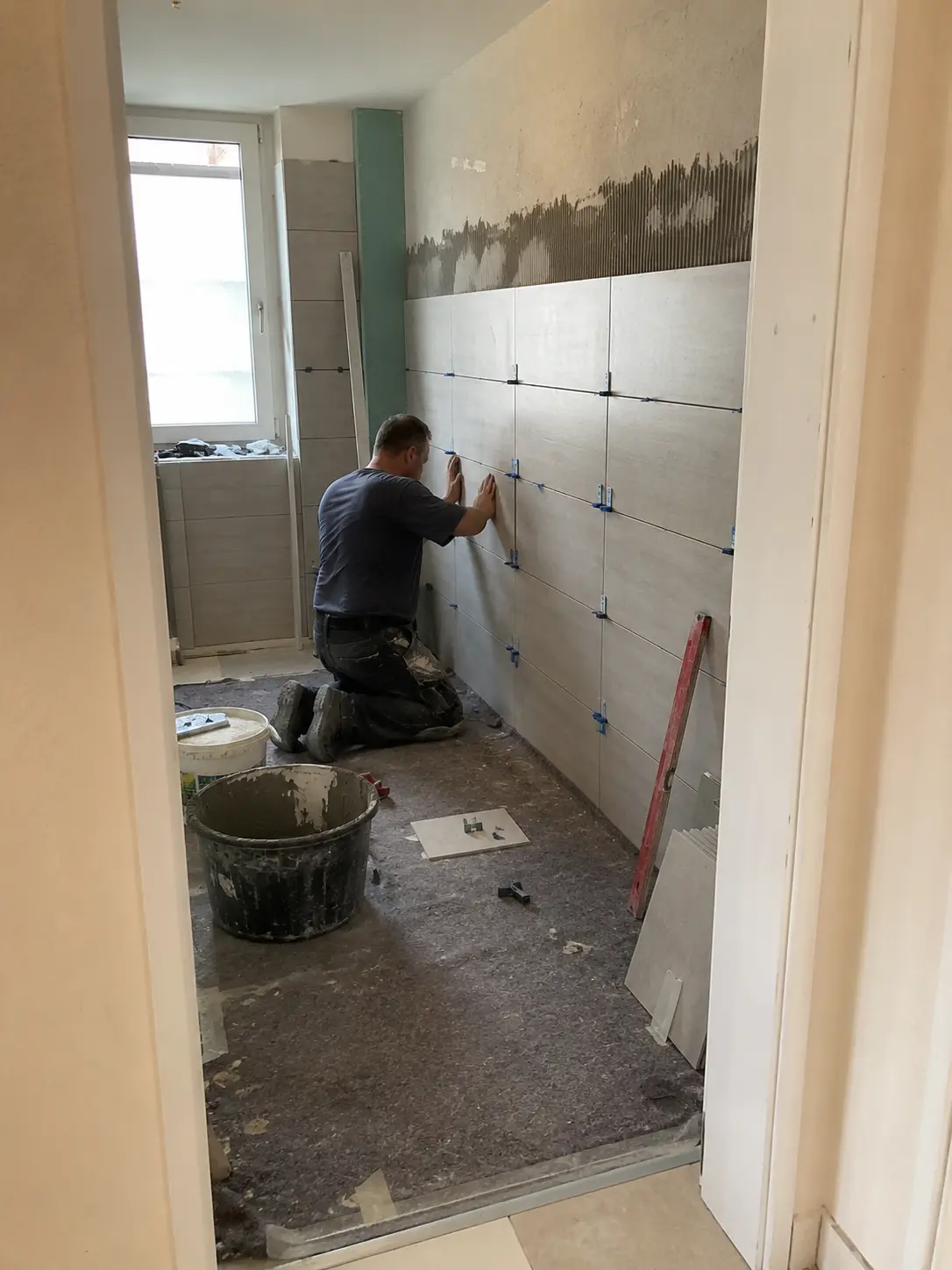 Fliesenleger beim Verlegen von Wandfliesen im Badezimmer Hamburg